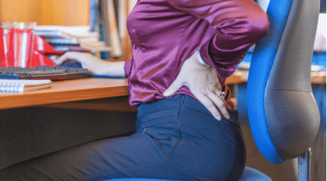 woman in chair holding her back