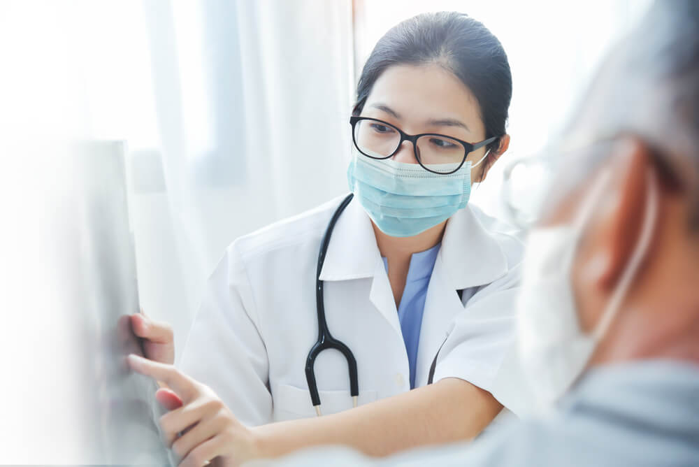 Female doctor pointing to an x-ray with patient in foreground