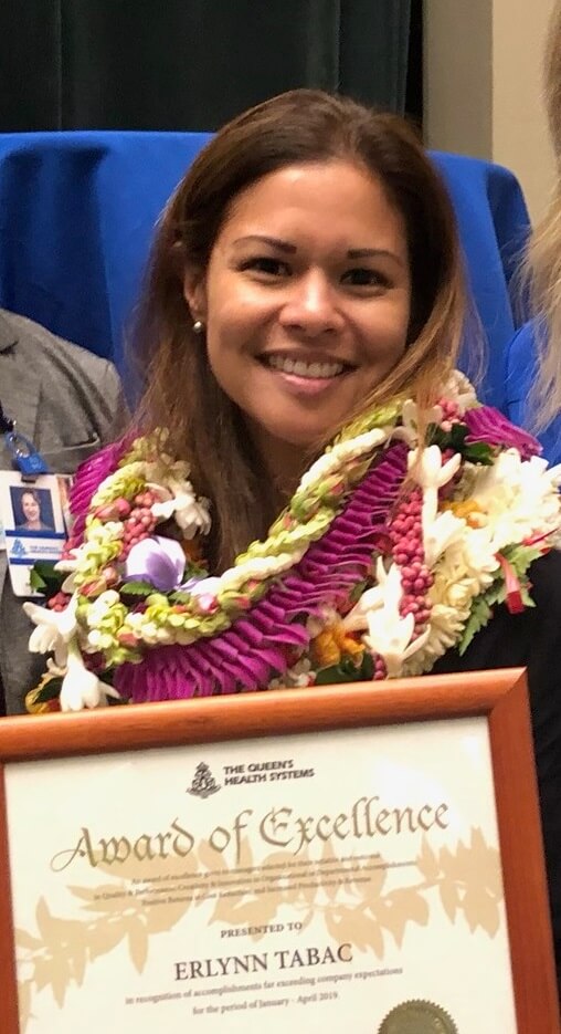 Erlynn Tabac wearing leis and holding her Award of Excellence