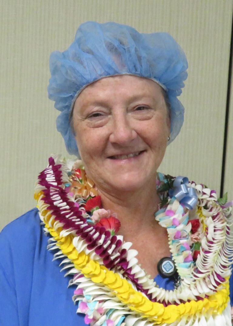 Headshot of Jeannette Oslund with leis and protective cap on