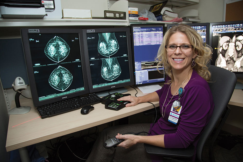 Female radiologist with scans in the back ground on monitors.