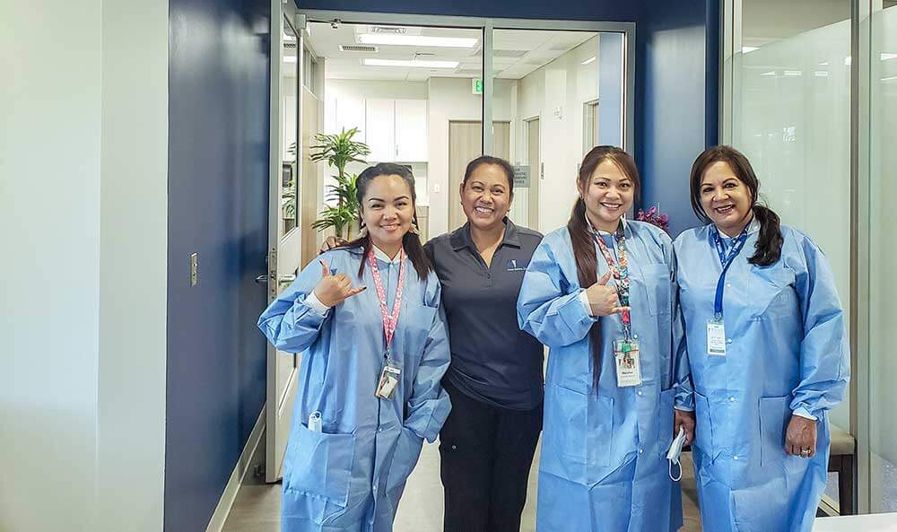 4 female medical staff members holding up shakas