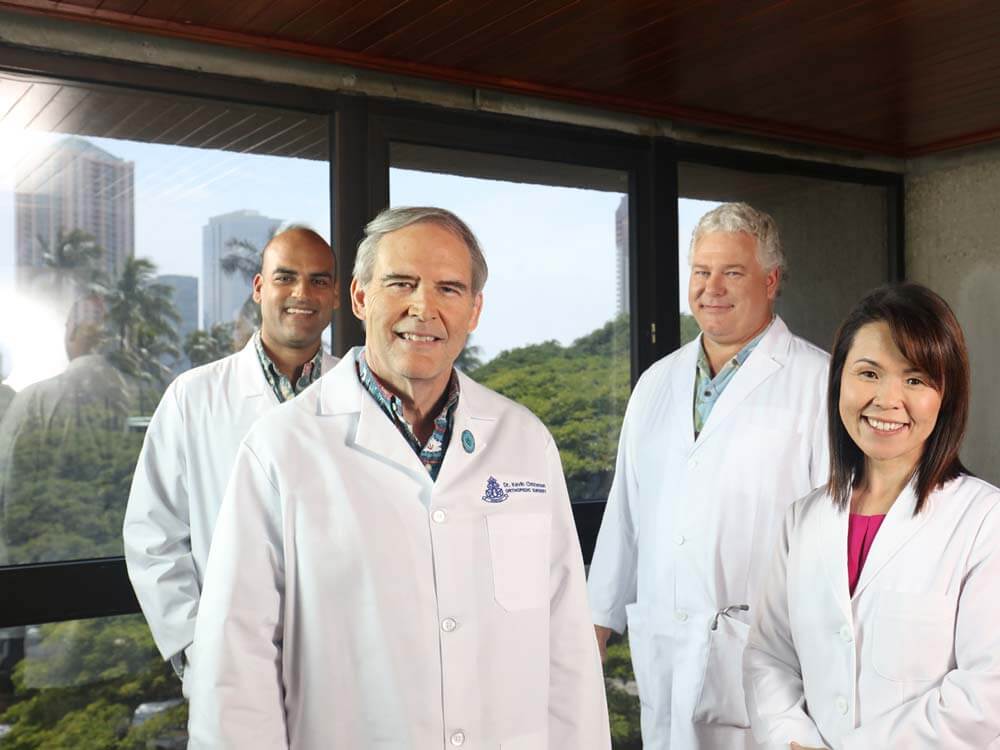 Group of 4 doctors standing by a window.