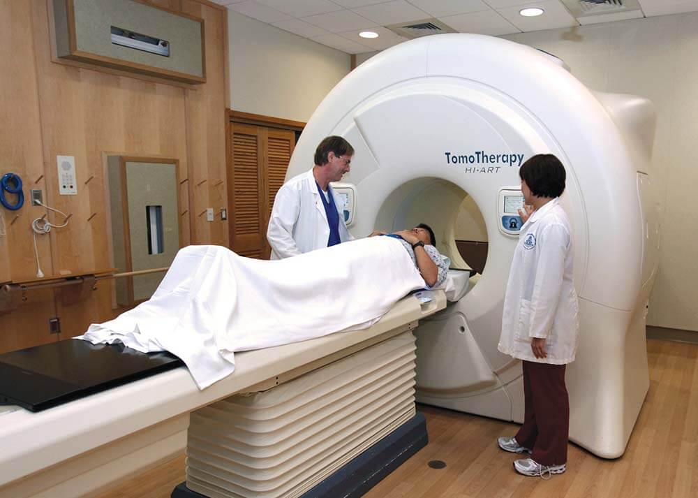 Doctors speak with patient preparing to go through a scanner.