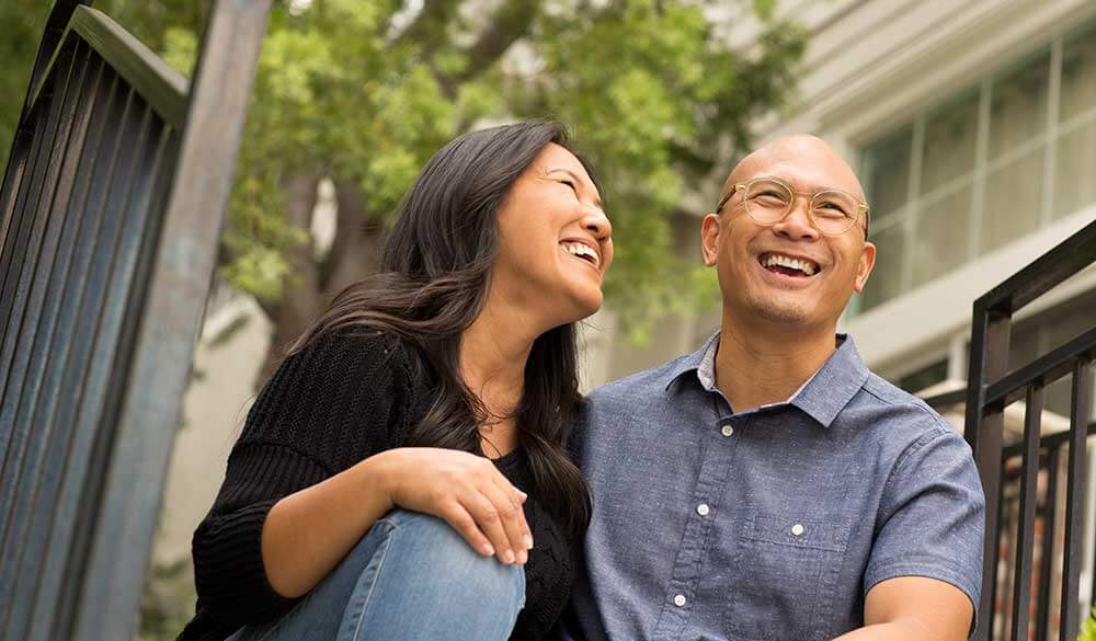 Couple smiles together on staircase.