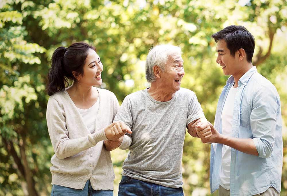 Sister and brother help guide their senior father on a walk