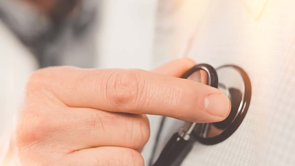Close up of hand holding stethoscope to a chest.