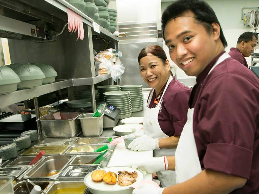Young man and woman prep food in a cafeteria