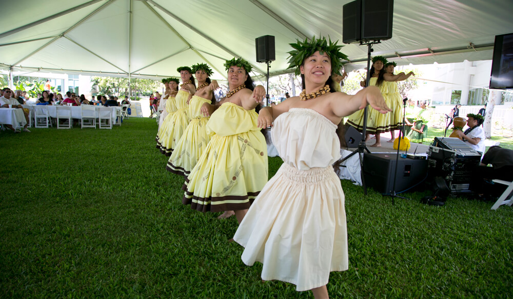 Group of women in dresses Hula dancing on stage.