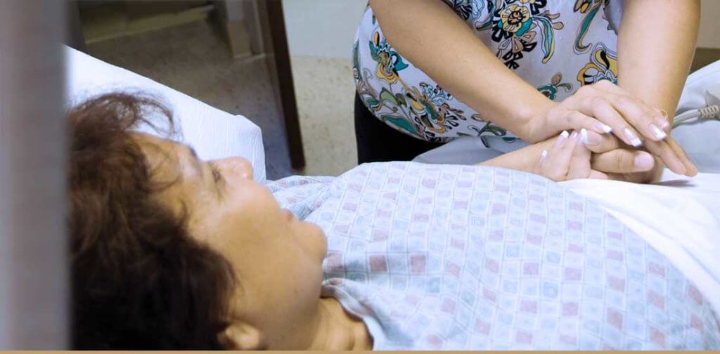 Close up of patient with her holding the hand of a nurse