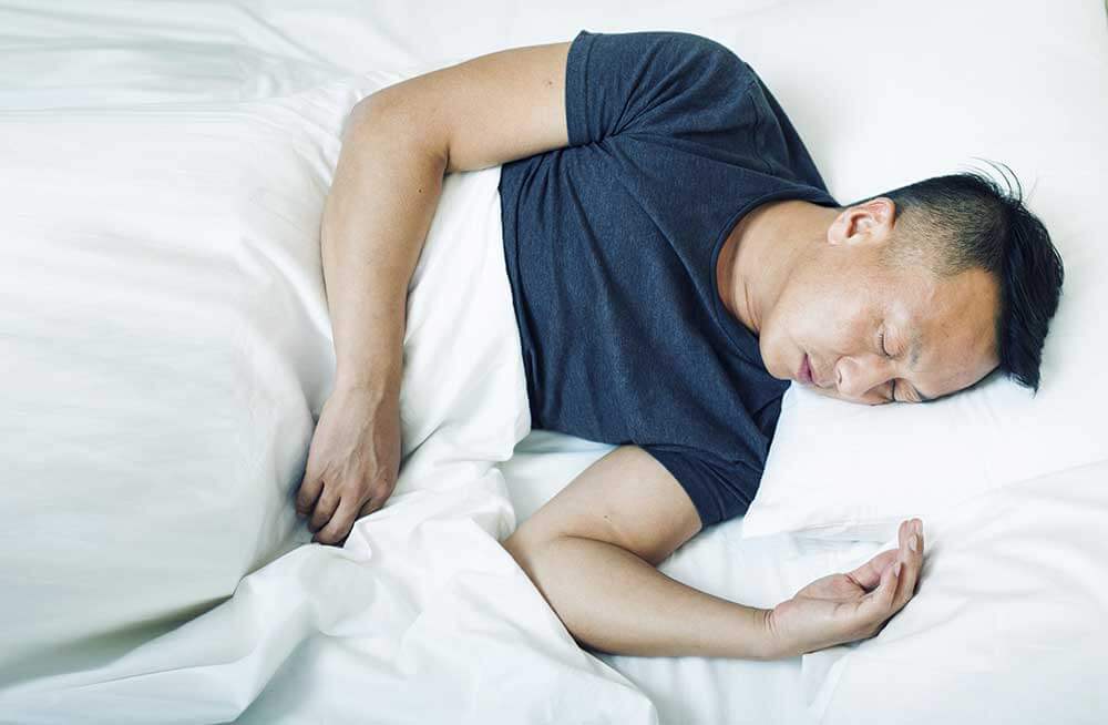 Man sleeping in white bed