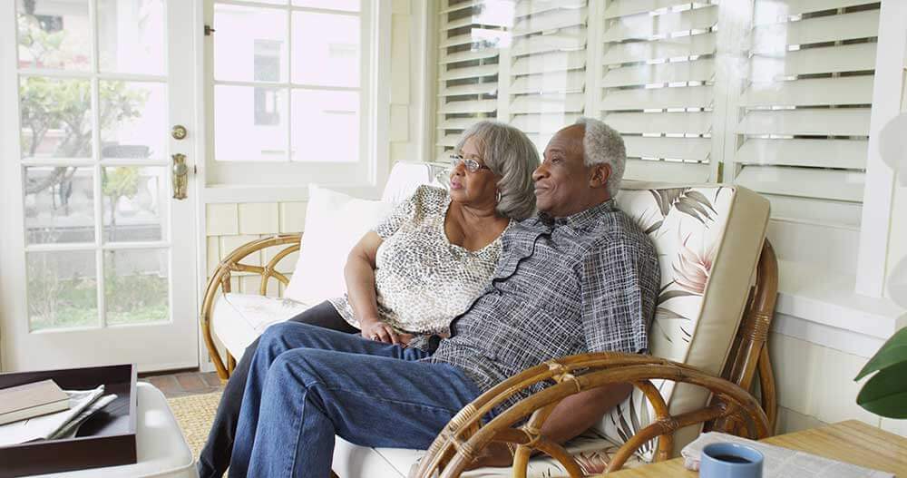 Senior couple sitting in sunroom on a floral couch
