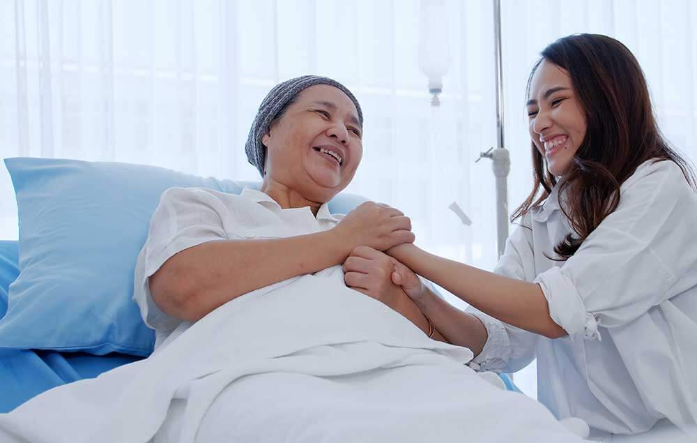 Ductor and cancer patient smile and hold hands