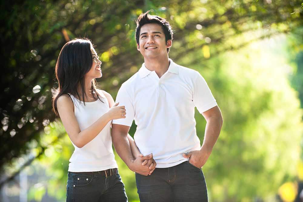 Woman holding mans hand and looking at him as they walk outside