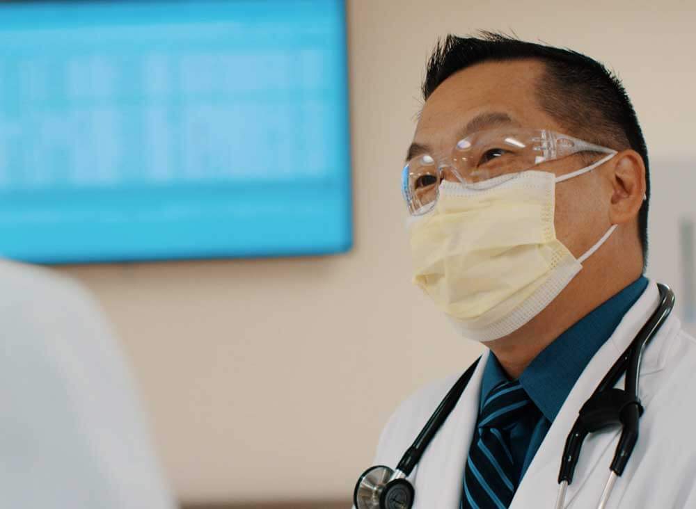Close up of male Doctor in a facemask with stethoscope around his neck.