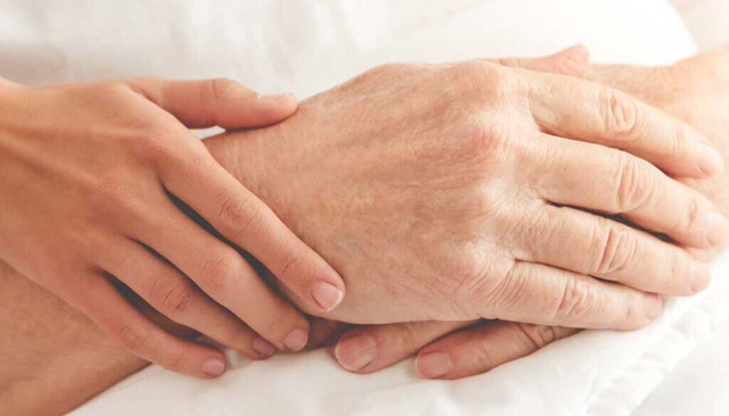 Close up of young hands embracing crossed hands of an elder.
