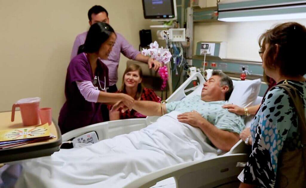 Female medical staff checking patient's wrist with his family in the room.